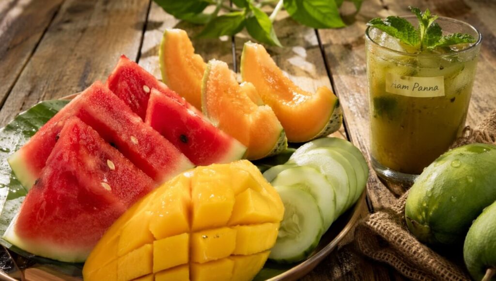 Ek plate mein kate hue taaza tarbuz, aam, aur kharbuja jo garmi mein dehydration se bachate hain.